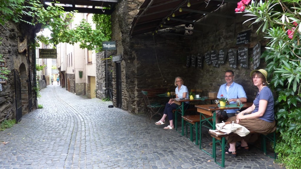 Gäste trinken Wein auf Bänken in der Altstadtgasse