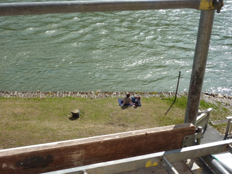 Zwei Personen sitzen auf Wolldecke am Rheinufer