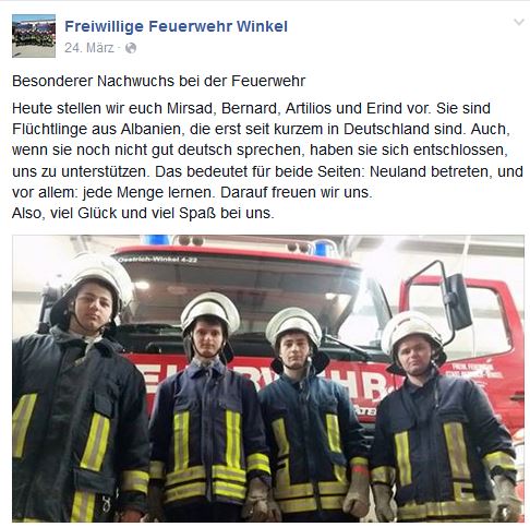 Vier junge Männer in Feuerwehr-Montur vor Einsatzwagen